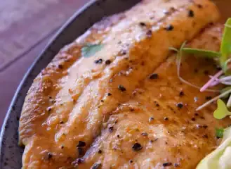 Coxa de frango grelhada com tempero, servida com salada fresca.