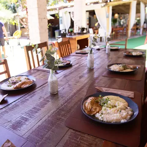 Imagem de uma mesa de jantar ao ar livre na Villa Verde, com pratos de comida e ambiente aconchegant.